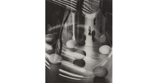 A black-and-white photograph of eggs surrounded by light, shadows, and reflections.