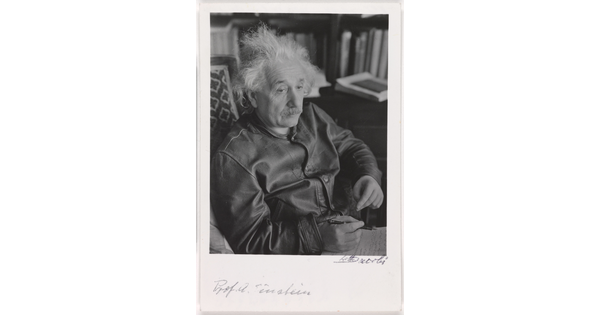 A black-and-white photograph of a seated older White man with wild white hair and mustache above handwritten notes.