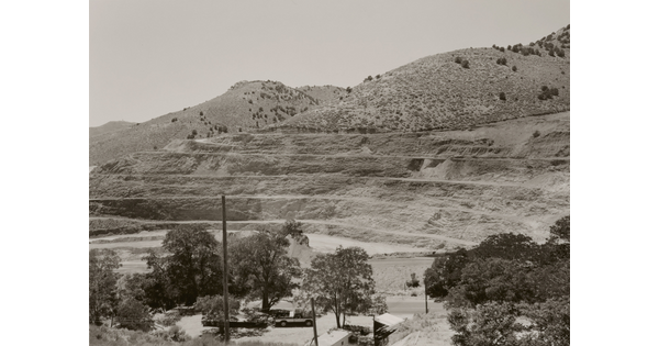 A black-and-white photograph of a mountainside that has been strip mined and the town below.