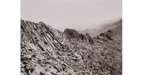 A black-and-white photograph of a rocky mountain ridge.