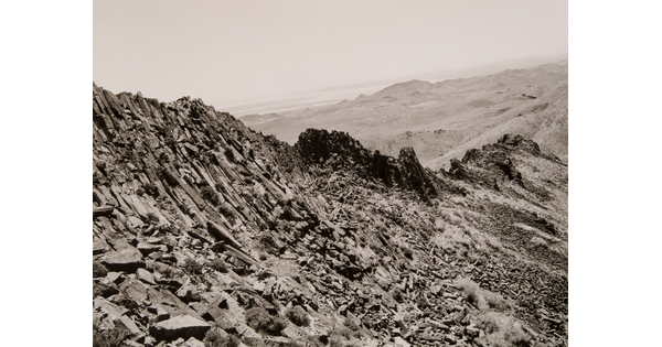 A black-and-white photograph of a rocky mountain ridge.