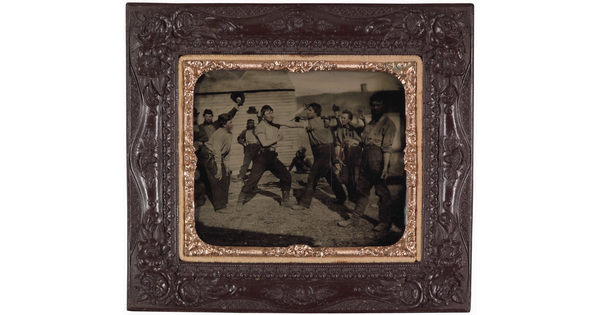 A framed black-and-white photograph of two men pretending to fight surrounded by other men who are watching.