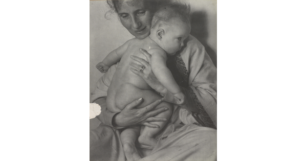 A black-and-white photograph of a White woman holding a naked baby to her chest.
