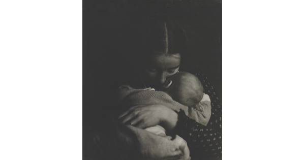 A black-and-white photograph of a White woman holding an infant to her chest while she rests her cheek on the infant's cheek.