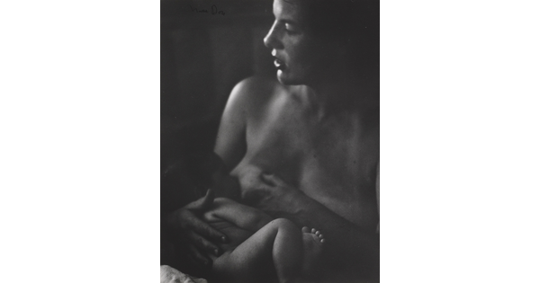 A black-and-white photograph of a White woman nursing a naked infant.