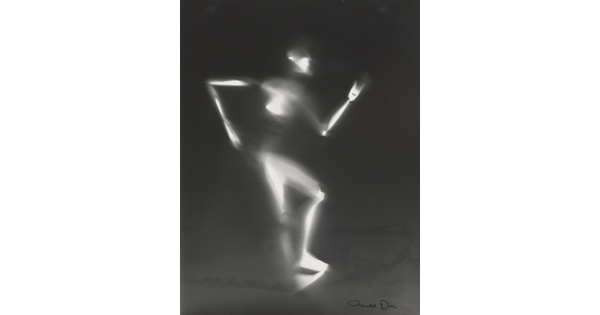 A black-and-white photograph of a white person-shaped puppet dancing on a black background.