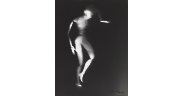 A black-and-white photograph of a white person-shaped puppet dancing on a black background.