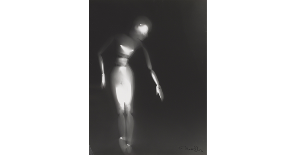 A black-and-white photograph of a white person-shaped puppet dancing on a black background.