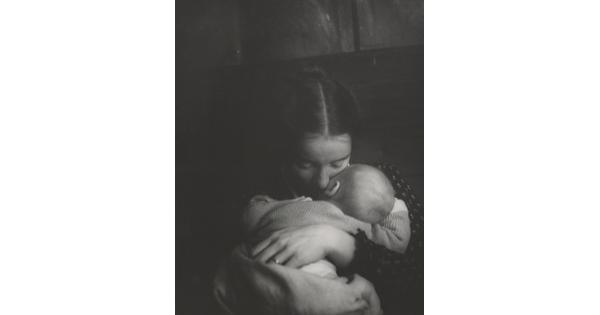 A black-and-white photograph of a White woman holding an infant to her chest while she rests her cheek on the infant's cheek.