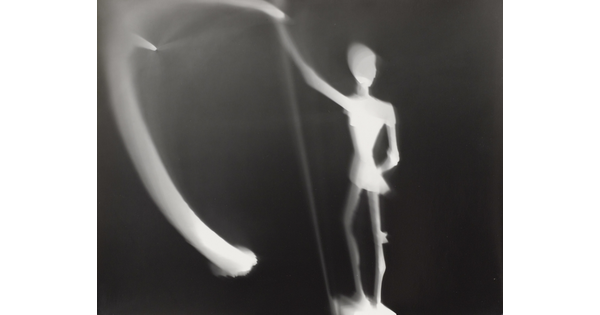 An abstract black-and-white photograph of an illuminated white figure and blurred lights against a black background.