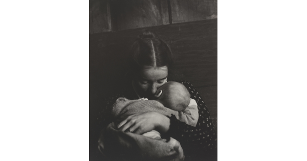A black-and-white photograph of a White woman holding an infant to her chest while she rests her cheek on the infant's cheek.