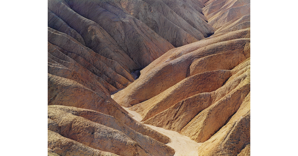 A color photograph of a desert valley between two arid mountains.