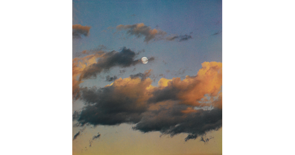 A color photograph of a full moon at dusk behind wispy, orange and dark clouds.