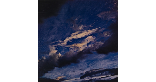 A color photograph of a dark blue sky streaked with dark and light clouds.