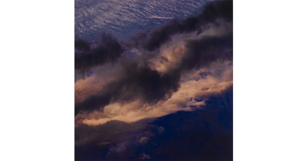 A color photograph of a dark blue sky streaked with dark and light clouds.