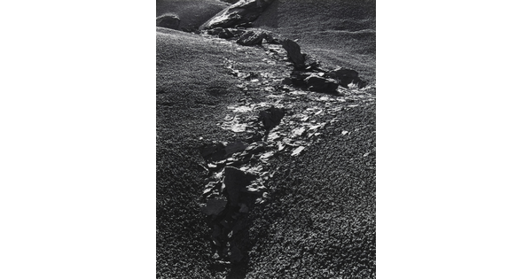 A black-and-white photograph of rocks and rock flakes bisecting a gravelly slope.