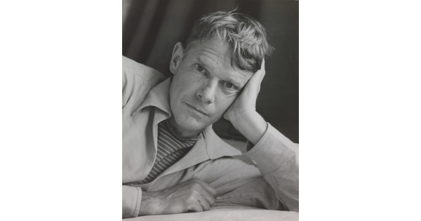 A black-and-white photograph portrait of a White man on his side, head resting on his hand, looking at the camera.