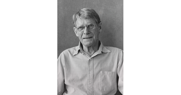 A black-and-white photograph of an older White man with short gray hair, wearing glasses and a button-down long-sleeved shirt.