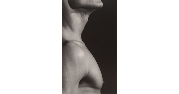 A close-up black-and-white photograph of a White man in profile from chin to just below the shoulders.