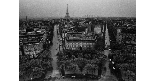 A black-and-white photograph taken from above of city streets fanning out toward the Eiffel Tower in the distance.