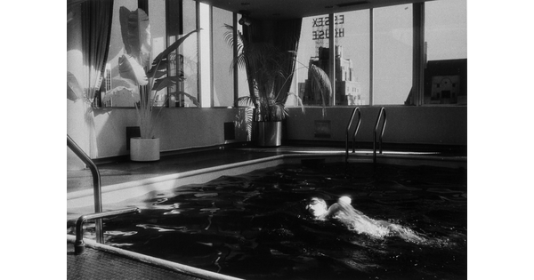 A black-and-white photograph of a person swimming in an indoor pool.
