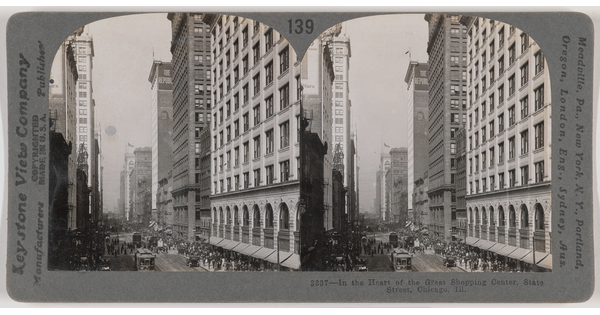 Two almost identical side-by-side black-and-white photographs of tall city buildings next to a busy street with pedestrians and streetcars.