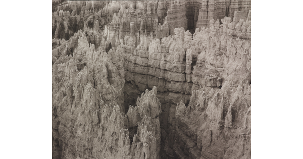 A black-and-white landscape photograph of banded rock formations in a canyon.