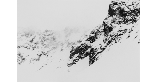 A black-and-white landscape photograph of a snowy mountain range.