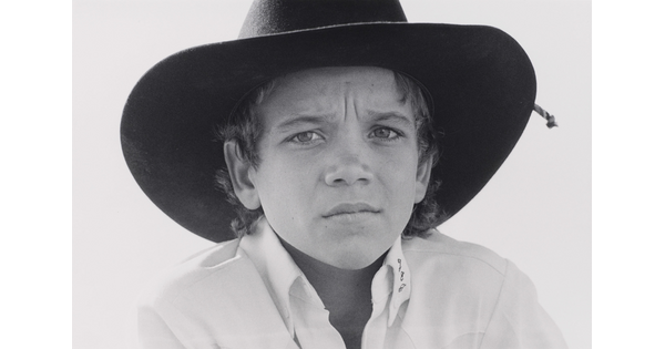A black-and-white close-up portrait photograph of a White boy with a serious expression wearing a cowboy hat.
