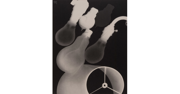 A black-and-white photograph of four incandescent lightbulbs placed diagonally above a lampshade.