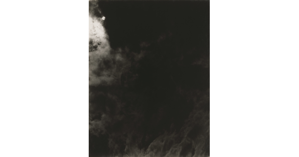 A black-and-white photograph of a dark, cloudy sky with the sun or moon shining through clouds.