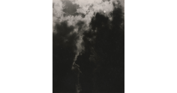 A black-and-white photograph of a dark, cloudy sky with the sun or moon shining through clouds.
