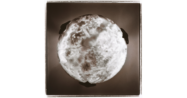 A black-and-white photograph looking up at a round ceiling light fixture with a surface that resembles the sun.