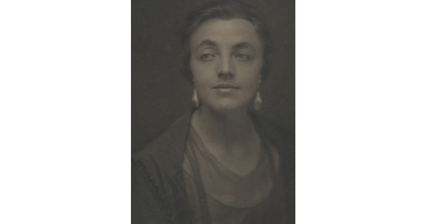 A sepia-toned portrait photograph of a White woman, hair tied back to show her dangling earrings.