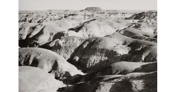 A black-and-white landscape photograph of sunlight on large, round desert rock formations.