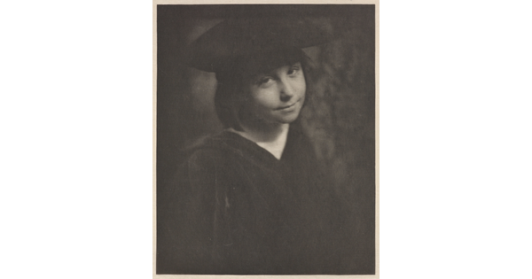 A black-and-white portrait photograph of a smiling, young White girl wearing a black hat and a black dress.