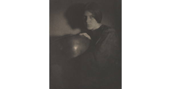 A black-and-white photograph of a White woman in dark clothing holding a bowl.