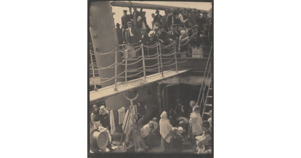 A black-and-white photograph of people outside on two decks of a crowded ship.