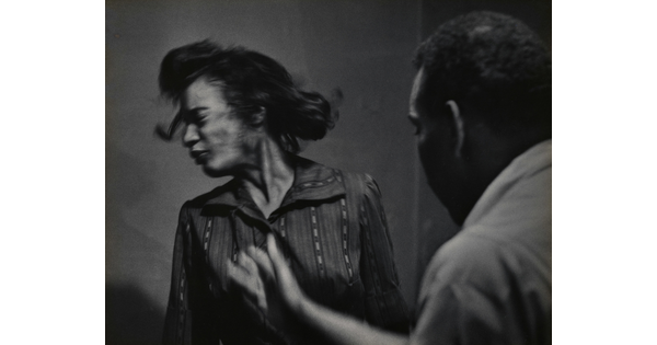 A black-and-white, mid-action photograph of a Black man who has just slapped a Black woman whose face turns away in reaction.