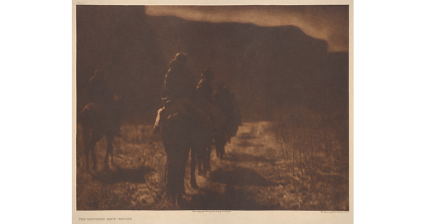 A dark, sepia-toned photograph of people on horseback riding away from the viewer.