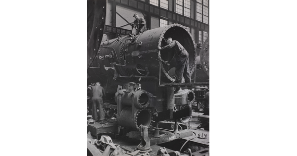 A black-and-white photograph of a few men building a locomotive car.