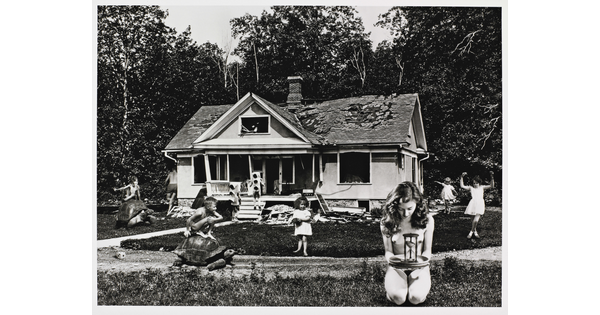A black-and-white photograph of superimposed children playing on the lawn of an abandoned house.