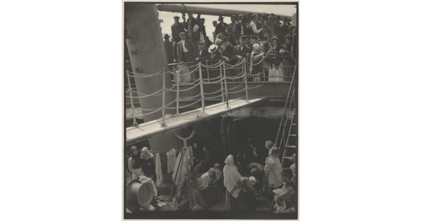 A black-and-white photograph of people outside on two decks of a crowded ship.