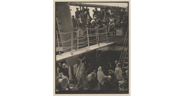 A black-and-white photograph of people outside on two decks of a crowded ship.