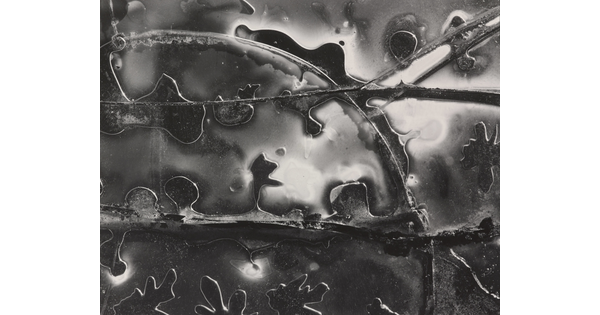 A black-and-white abstract photograph of glossy and transparent shapes and lines.