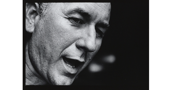 A black-and-white close-up photograph of the face of a White man who appears to be speaking.