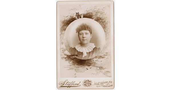 A sepia-toned, circular portrait photograph of a woman with curly hair in a lace, high-collared dress and decorative border that includes owls.