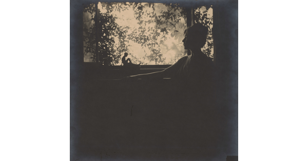 A black-and-white photograph of a silhouette of a woman in profile in front of a garden window.