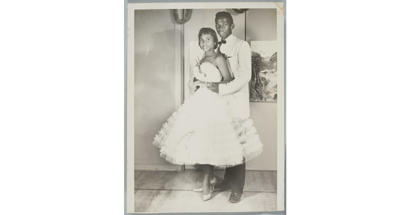 A black-and-white photograph of a Black couple in formal dress at a dance.
