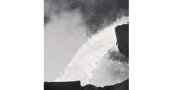 A black-and-white photograph of a close up of molten metal being poured.